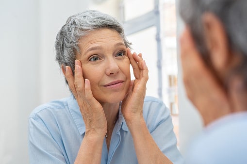Woman examining her face in a mirror