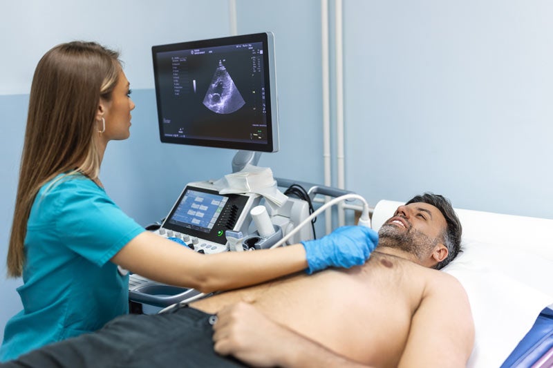 Technician checking man's heart in exam room