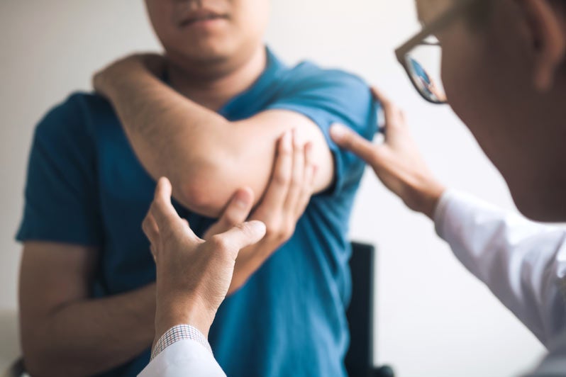 Doctor examining man's elbow