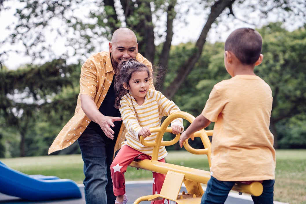 Father playing on seesaw with son and daughter