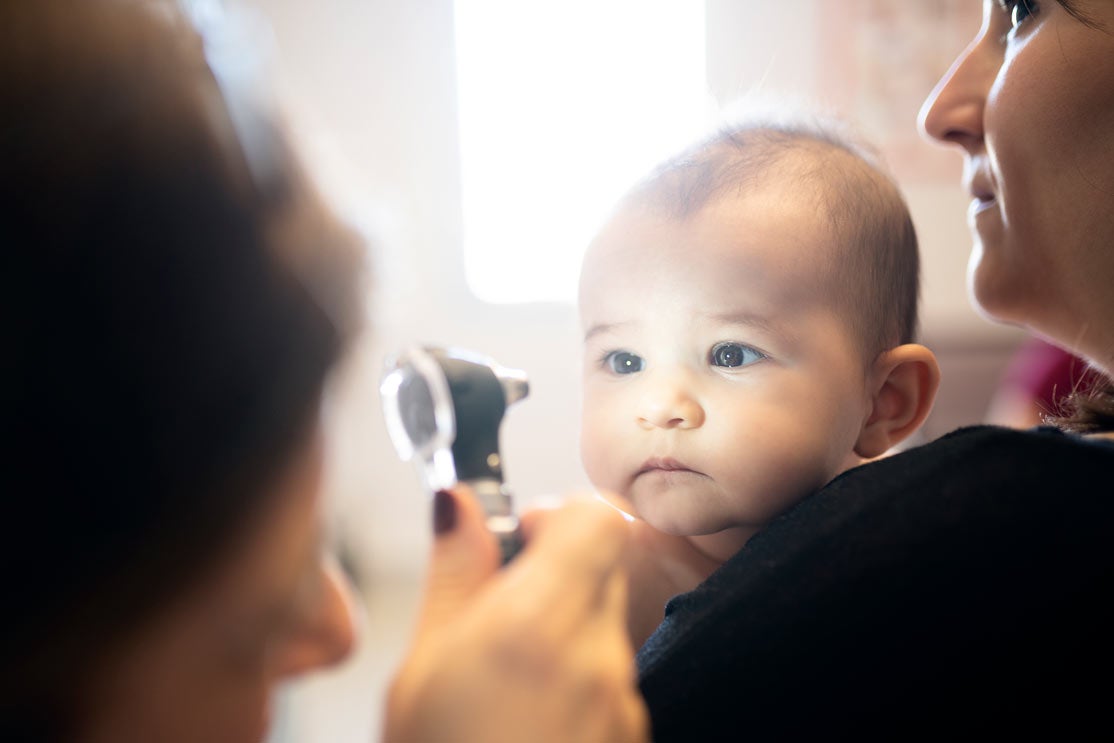 Baby getting eyes examined by doctor with ophthalmoscope 