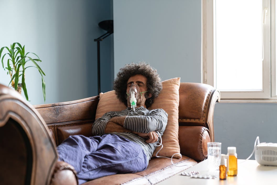 Man lying on couch using nebulizer for COPD