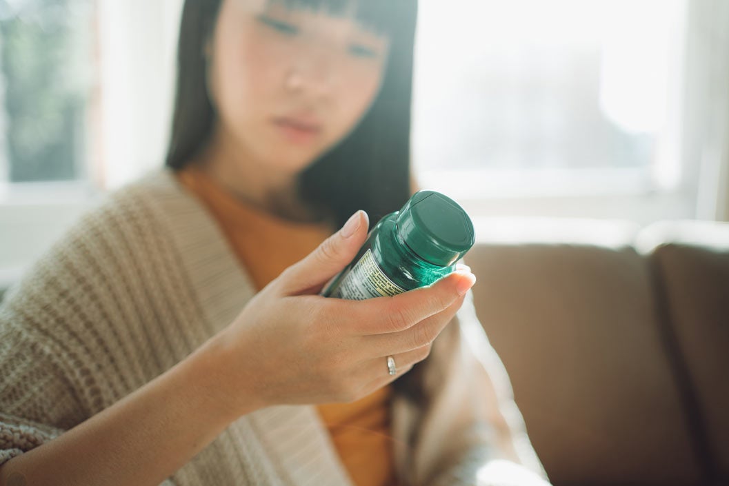 Out of focus woman looking at natural supplement bottle