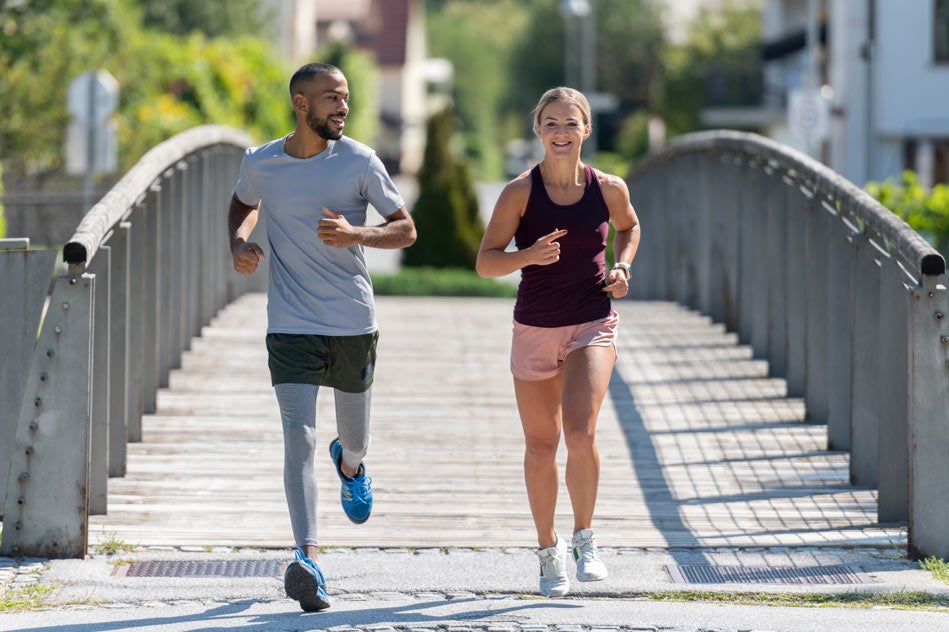 Man and woman running together across a bridge