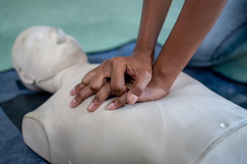 Closeup hands practicing chest compressions on a CPR training dummy