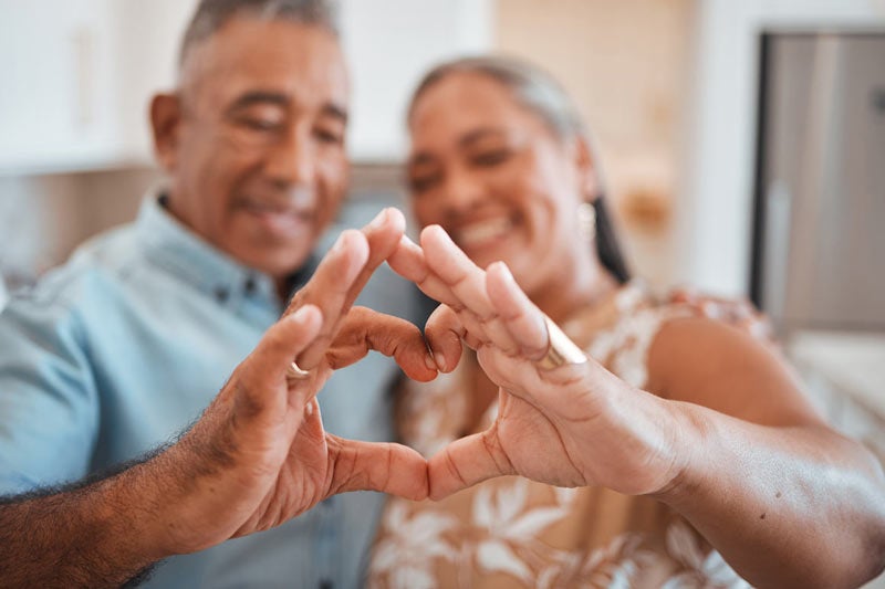 Mature couple making a heart with their hands