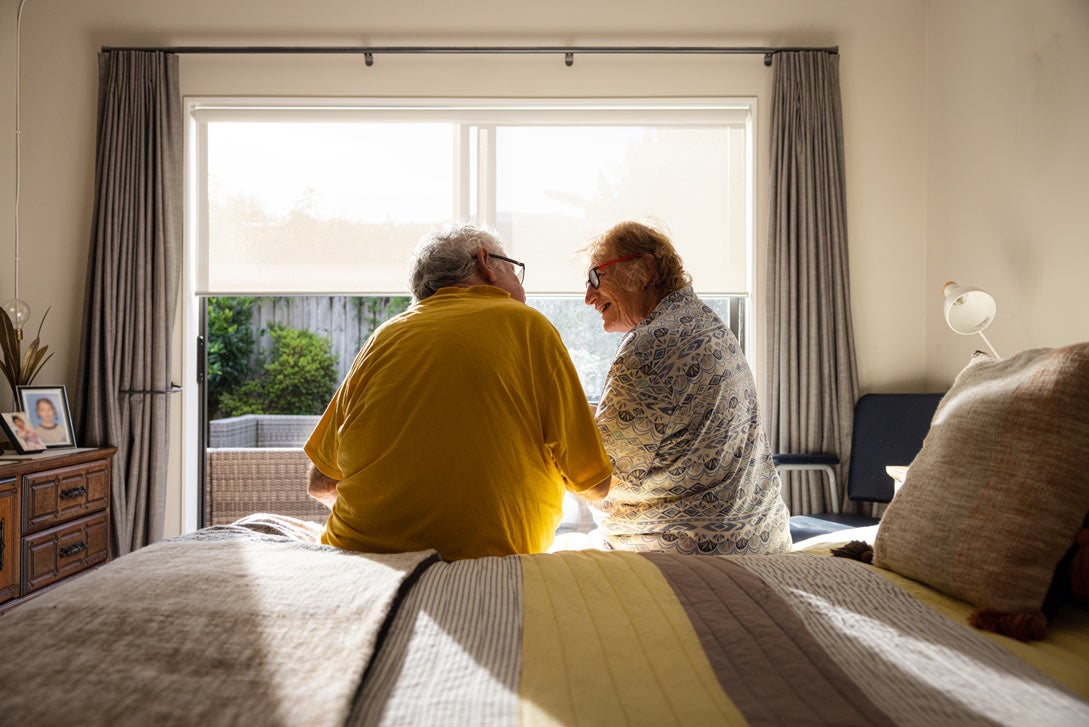 Back shot of senior couple sitting on edge of bed