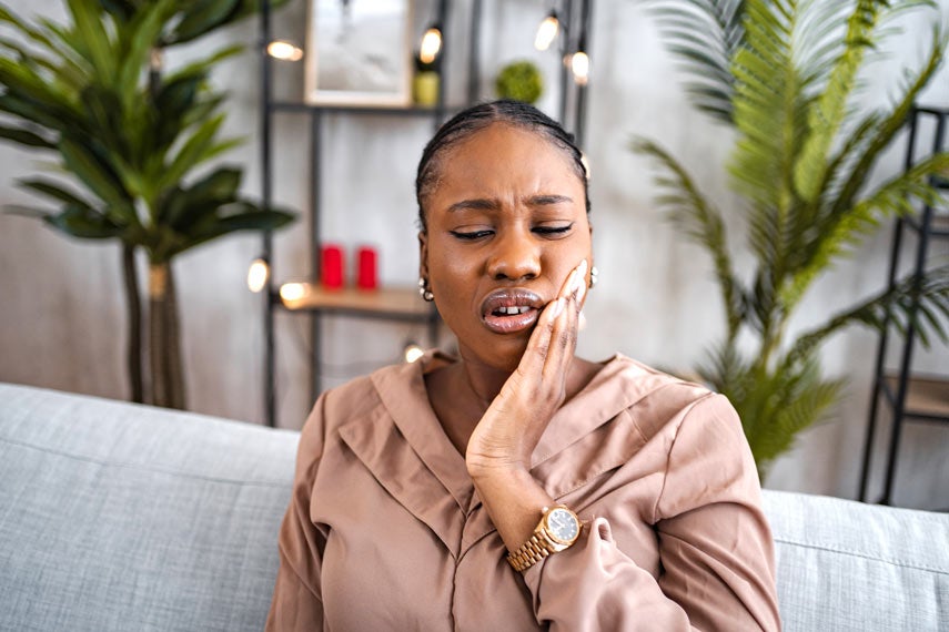 Woman experiencing toothache while sitting at home