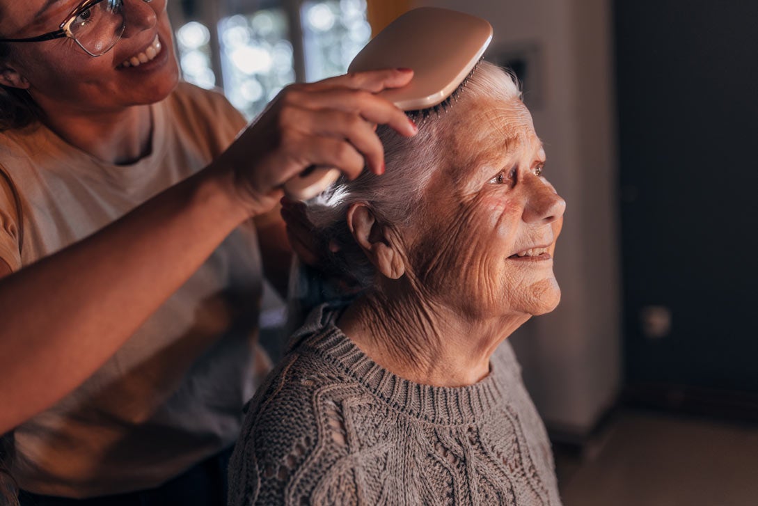 Granddaughter combing grandmother's hair