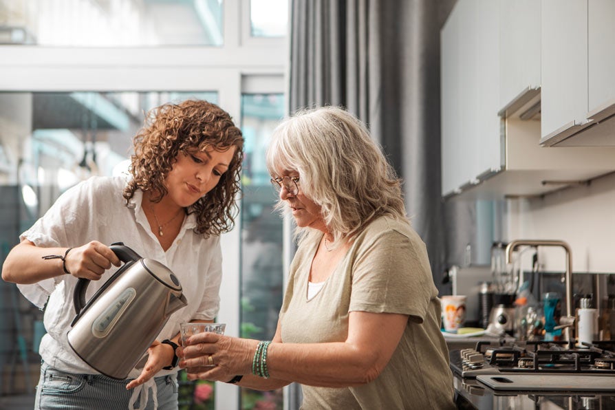 Older woman getting help pouring hot water