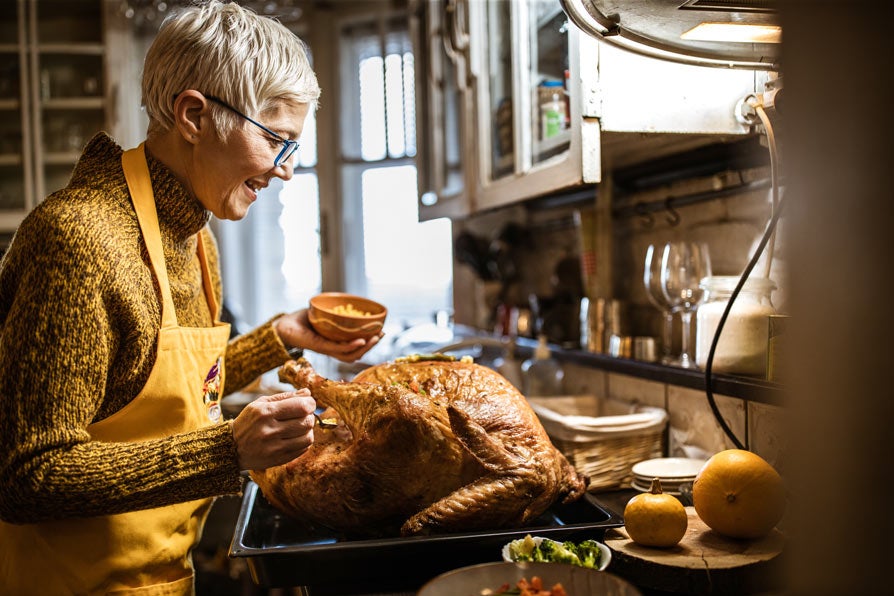 Woman cooking turkey in kitchen