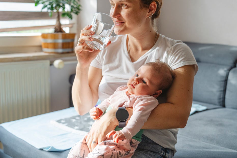 Mom drinking water holding daughter