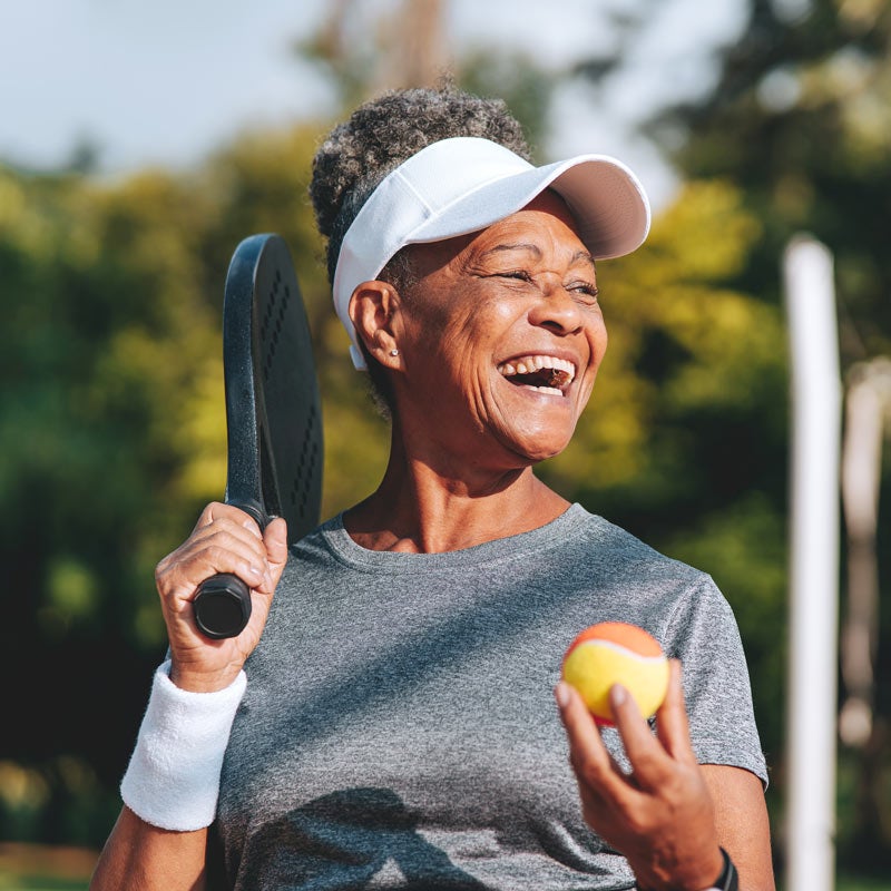 Happy senior woman playing tennis