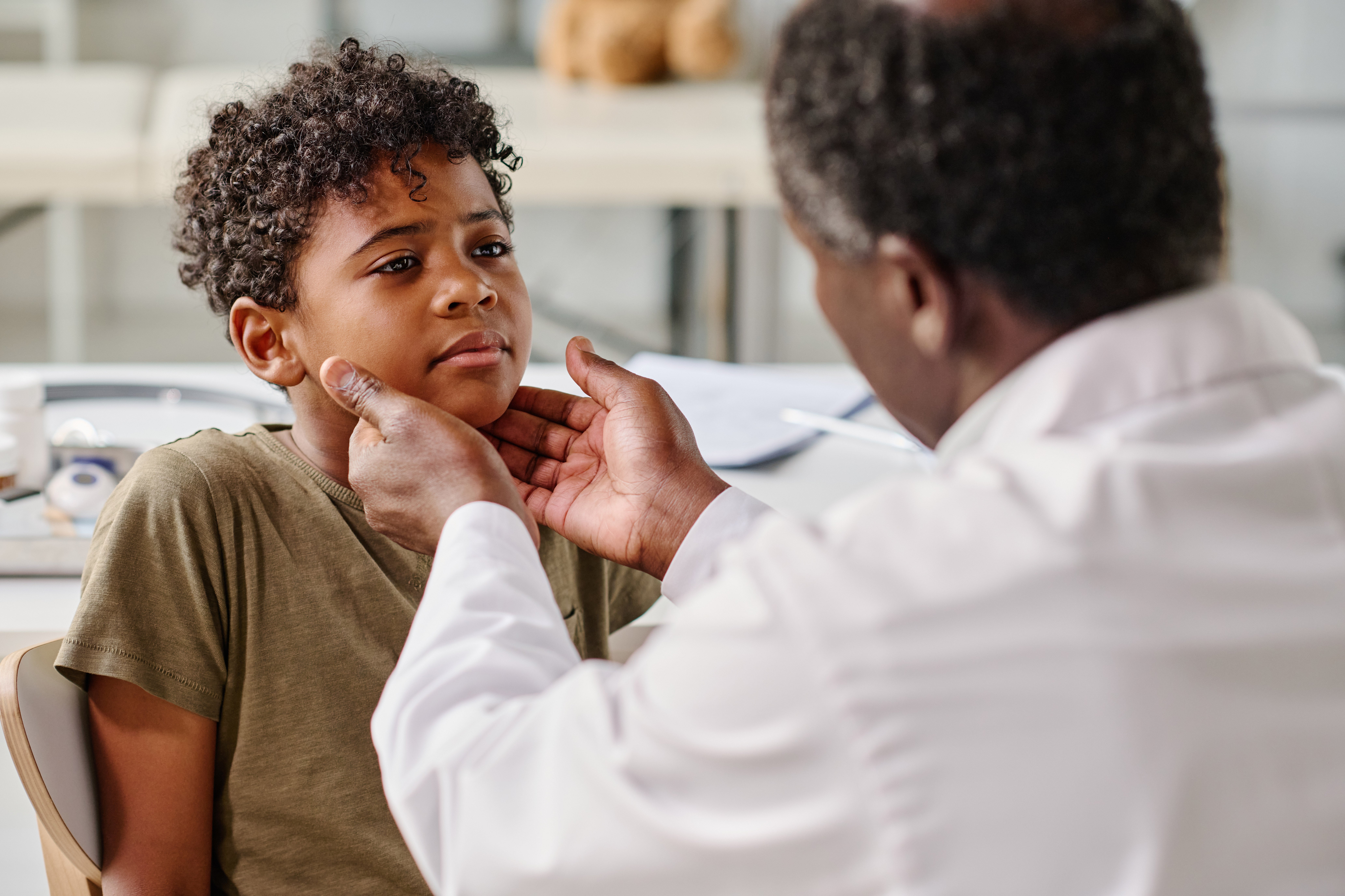 Pediatrician inspecting child for tonsillitis