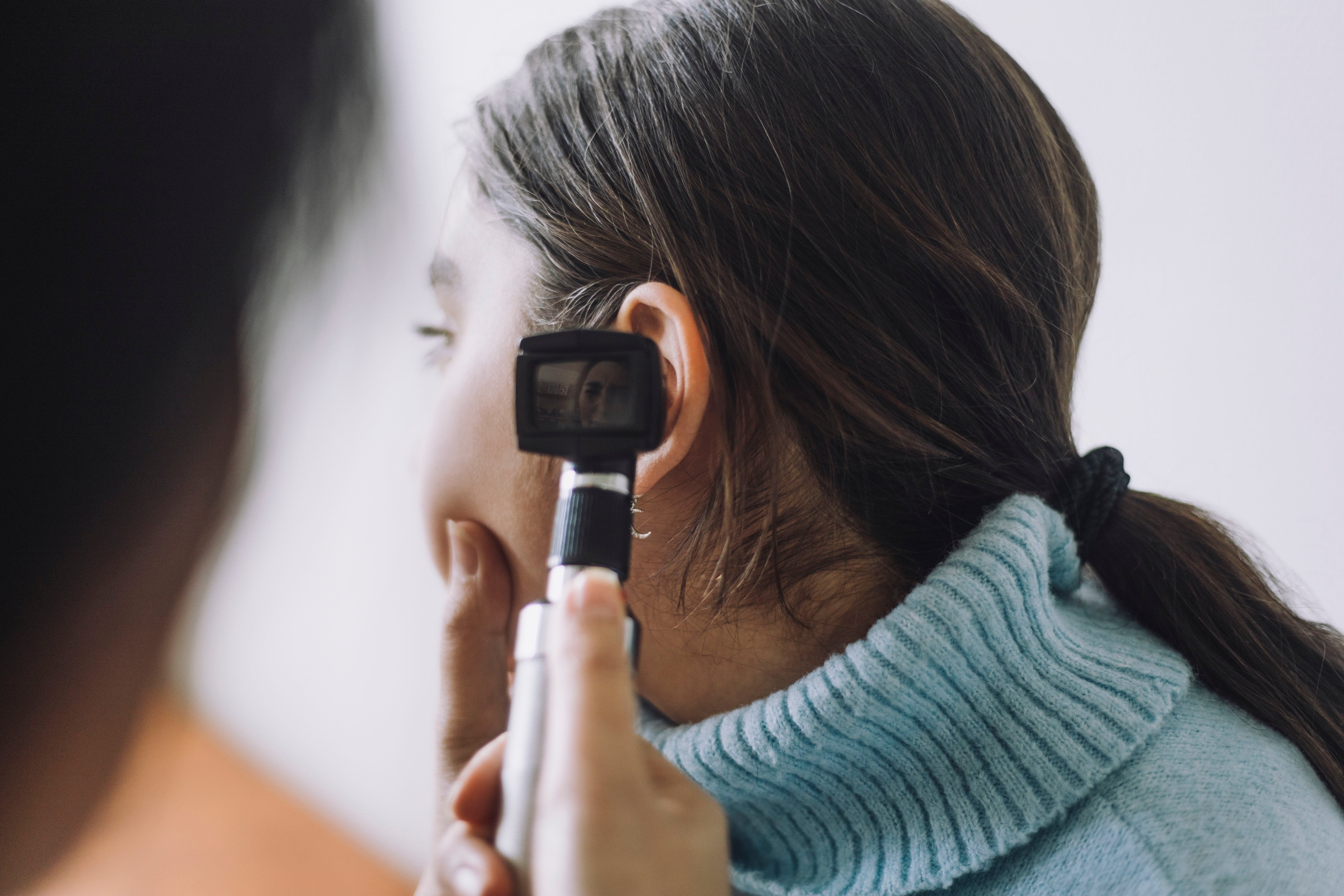 Doctor inspecting women's ear in-office