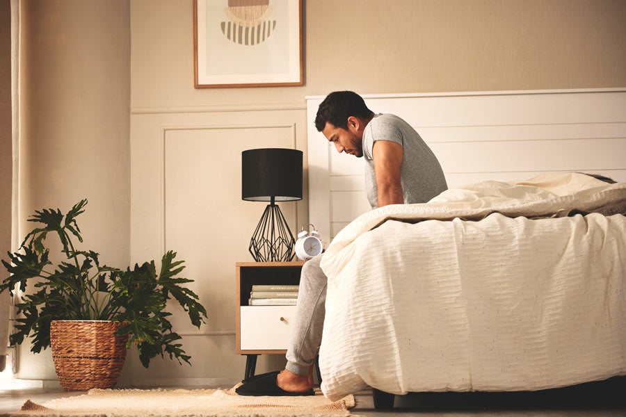 Man deep in thought while sitting on bed