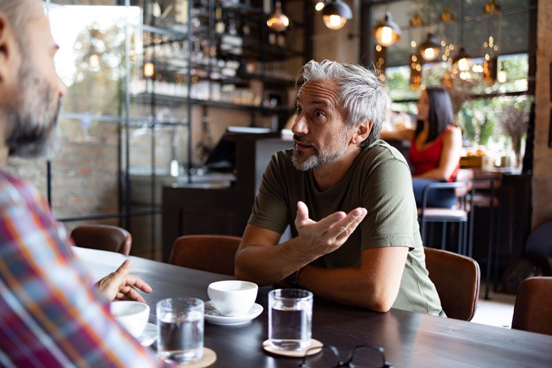 Two older men chat over coffee